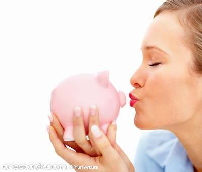 Pretty young female kissing piggybank and  cop...